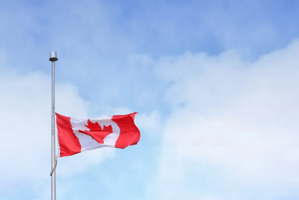 Drapeau du Canada flottant fièrement sous un ciel bleu, évoquant les opportunités d’un déménagement au départ de bordeaux vers le Canada