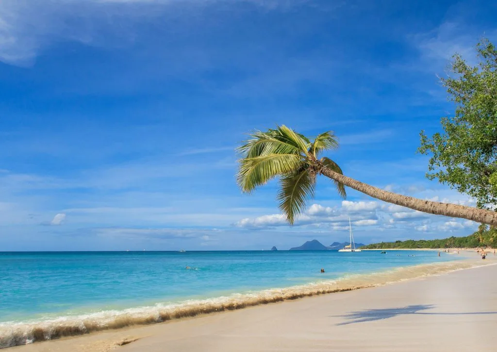 Plage idyllique en Martinique, avec sable fin et eaux turquoise, représentant une destination de rêve pour un déménagement en Martinique