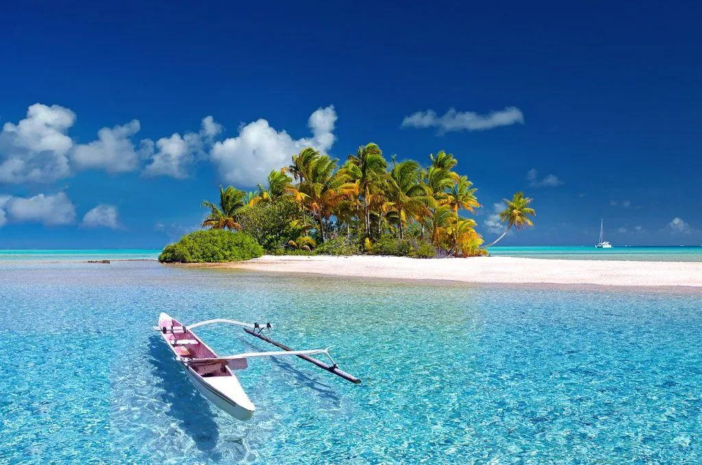 Petite île paradisiaque en Polynésie, entourée d'eaux turquoises et de plages de sable blanc, évoquant un cadre idyllique pour un déménagement en Polynésie